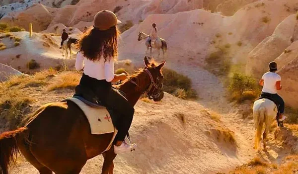 A romantic couple riding horses in Cappadocia during the sunset hour.