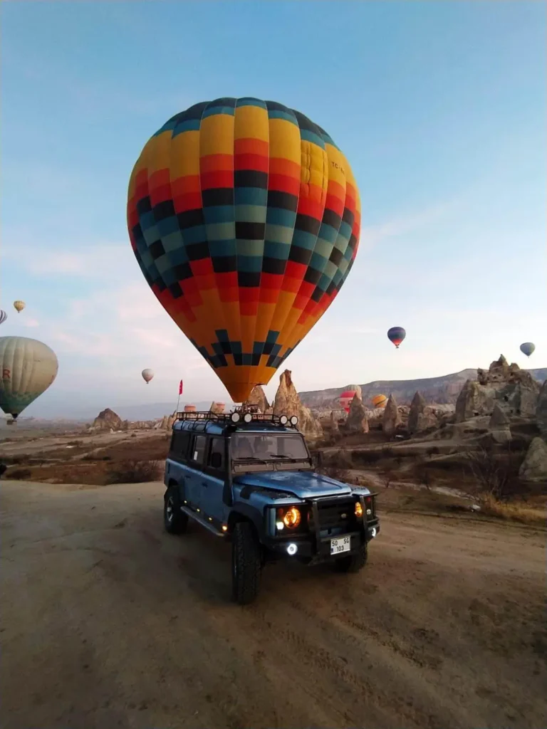 Private Jeep Safari tour in Cappadocia during sunset with hot air balloons in the background.